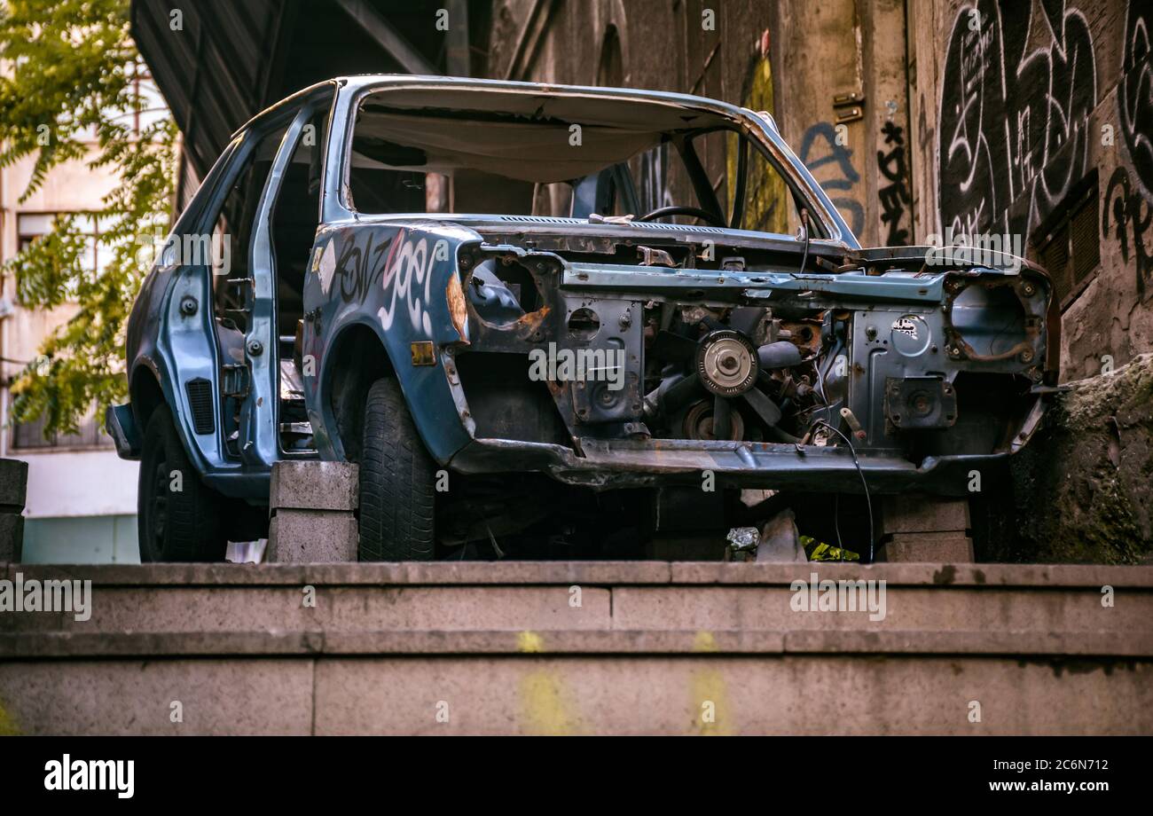 un'auto abbandonata di rottami, in piedi a parte sul marciapiede, all'aperto. Foto Stock