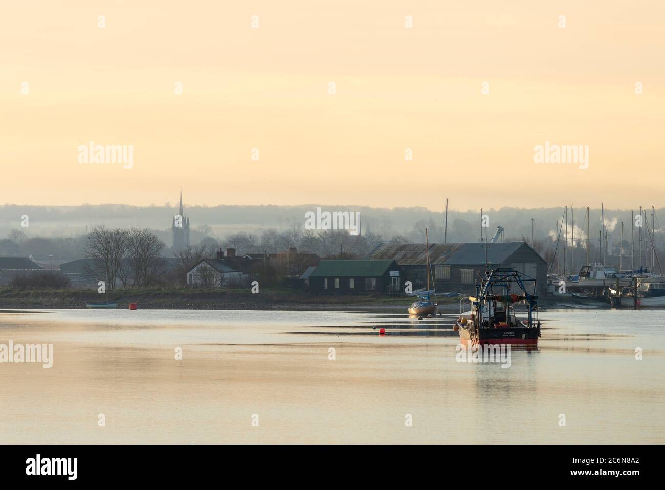 Barche sul torrente Faversham prese dalle paludi di Oare nel Kent. La chiesa gotica di Santa Maria della Carità di Faversham si può vedere in lontananza. Foto Stock