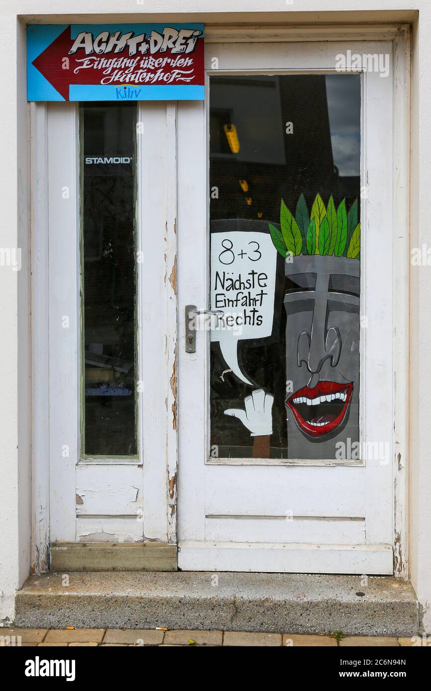 Faccia dipinta con i capelli del fogliame e bolla vocale sulla porta di vetro di Kiel, che conduce all'ingresso successivo tramite il puzzle matematico "8 + 3". Foto Stock
