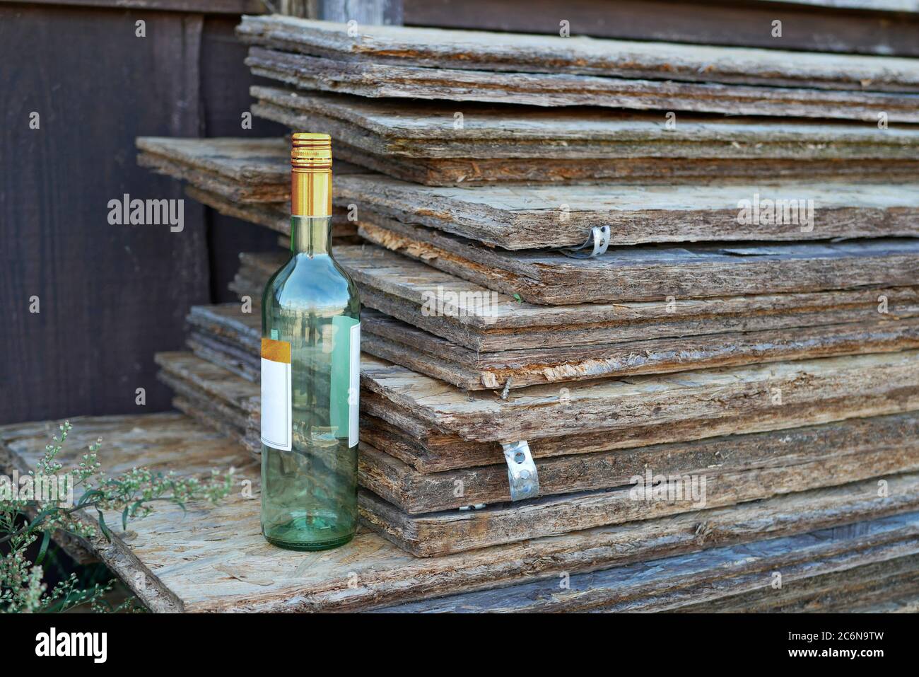 Una bottiglia di vino vuota su una pila di tavolette di truciolare Foto Stock