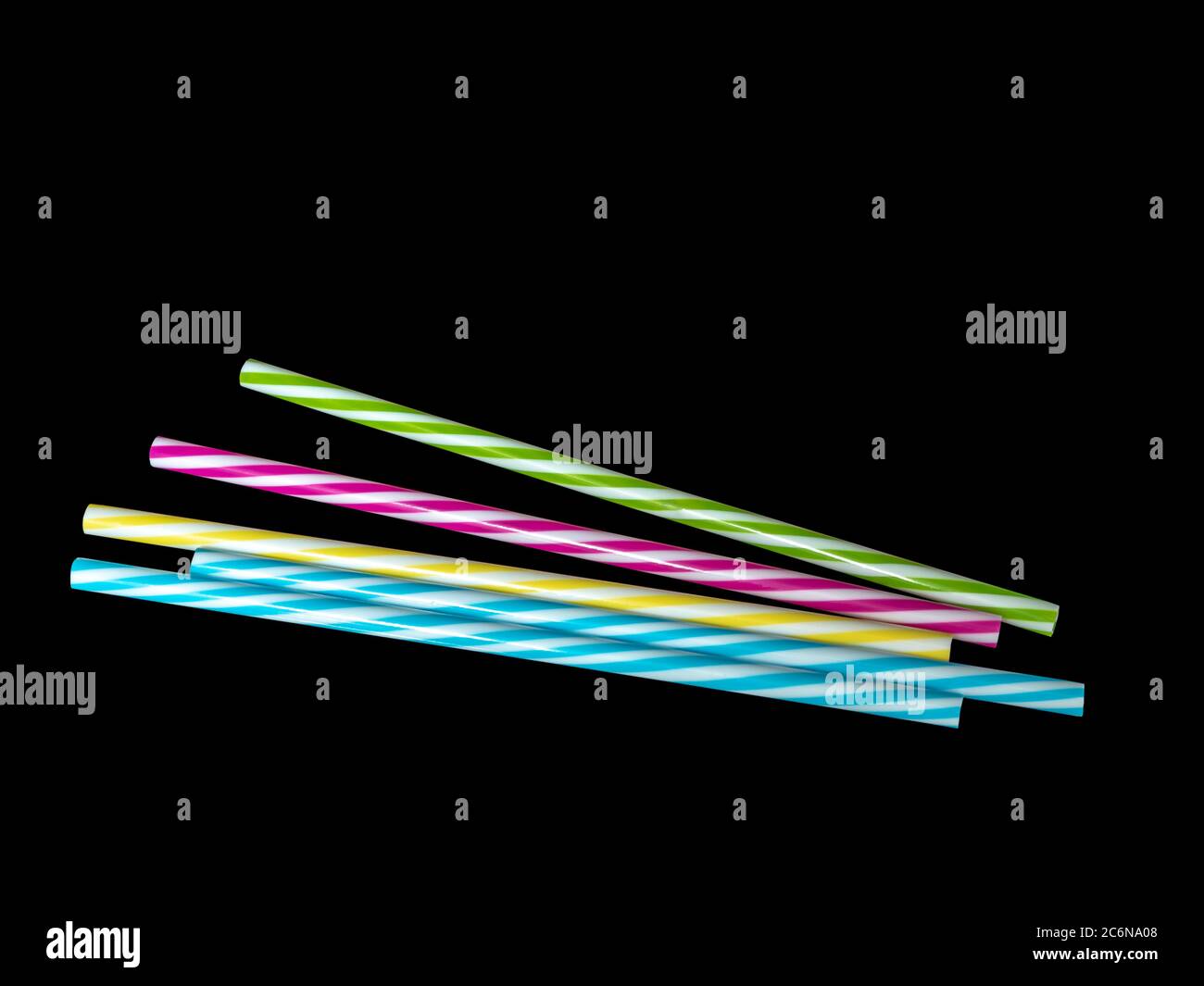 Pile di colorate paglia potabile in plastica a righe, sottoterra nera Foto Stock