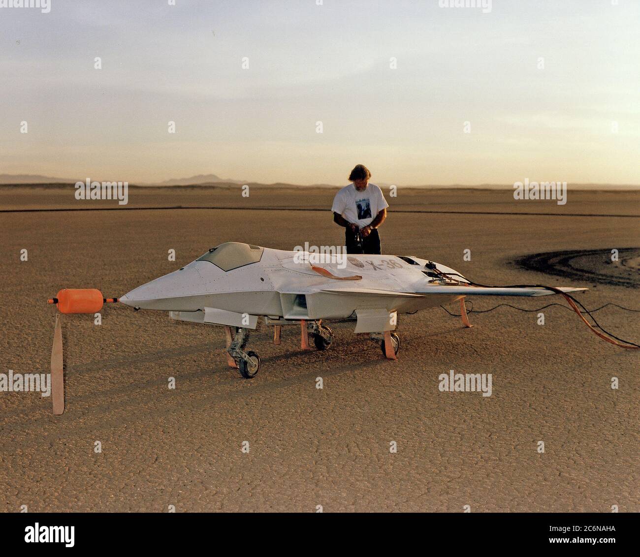 Illuminato dai raggi dell'alba del mattino sul lago Rogers Dry, adiacente al Dryden Flight Research Center della NASA, Edwards, California, un tecnico prepara l'aereo X-36 Tailless Fighter Agility Research pilotato a distanza per il suo primo volo il 17 maggio 1997. Foto Stock