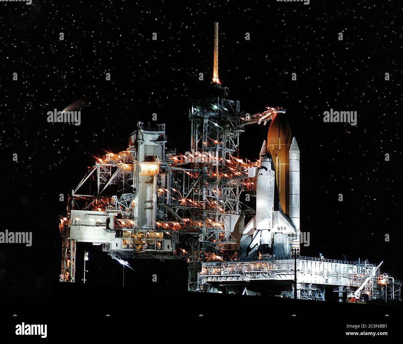 La navetta spaziale Columbia, presto disponibile, riceve una visita in volo dalla Comet Hale-Bopp (mostrata come la striscia al centro di sinistra) in attesa del lancio della missione STS-83. Questa foto è stata scattata la notte prima del previsto liftoff il 4 aprile 1997. La struttura di servizio rotante sul Launch Pad 39A è stata spostata indietro prima dell'inizio delle operazioni per alimentare il serbatoio esterno. L'obiettivo primario del volo STS-83 è quello di far funzionare il Microcitity Science Laboratory-1 (MSL-1), che testerà alcuni hardware, strutture e procedure che saranno utilizzate sulla Stazione spaziale Internazionale Foto Stock