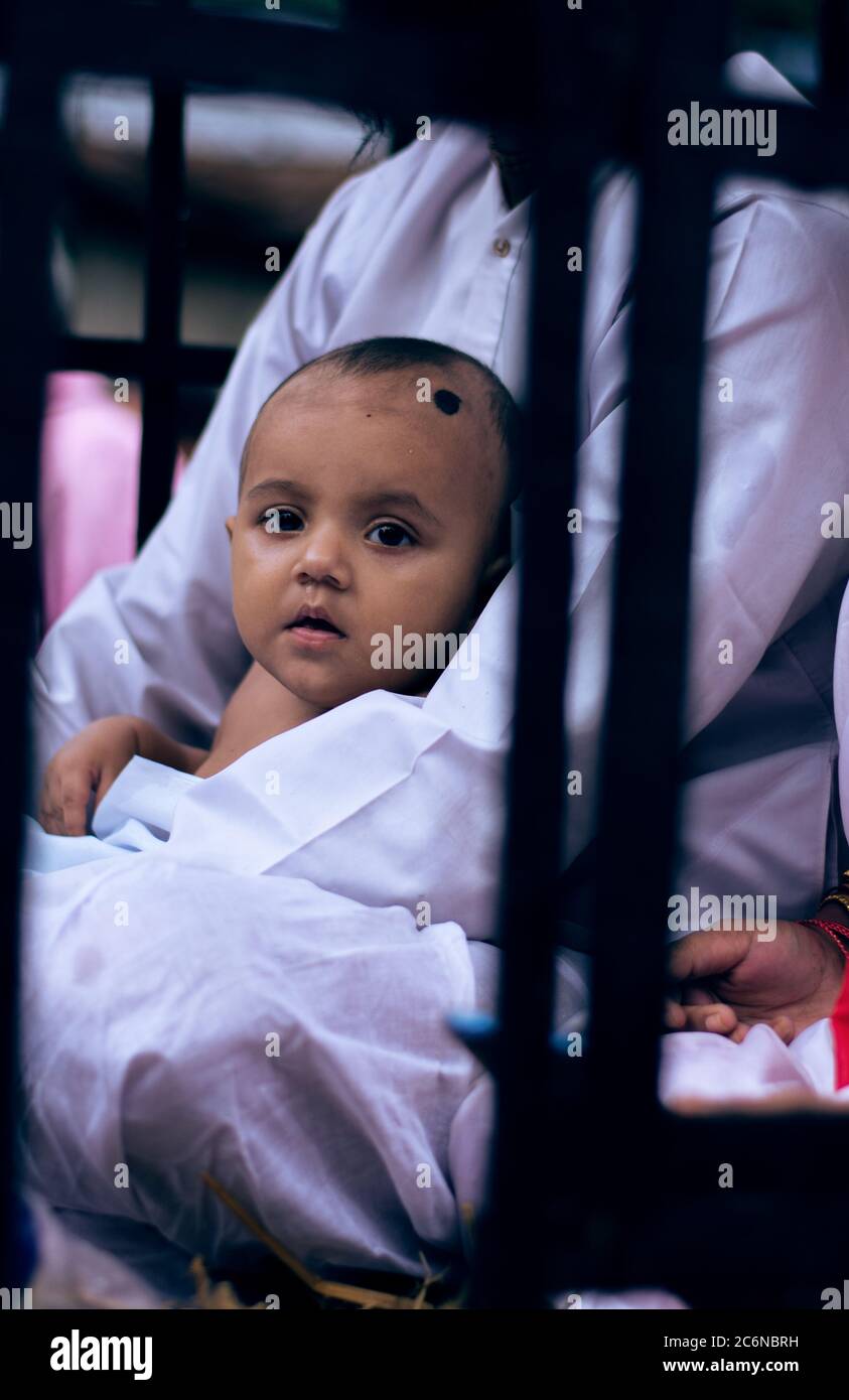 Un bambino che guarda la macchina fotografica dal suo grembo paterno Foto Stock