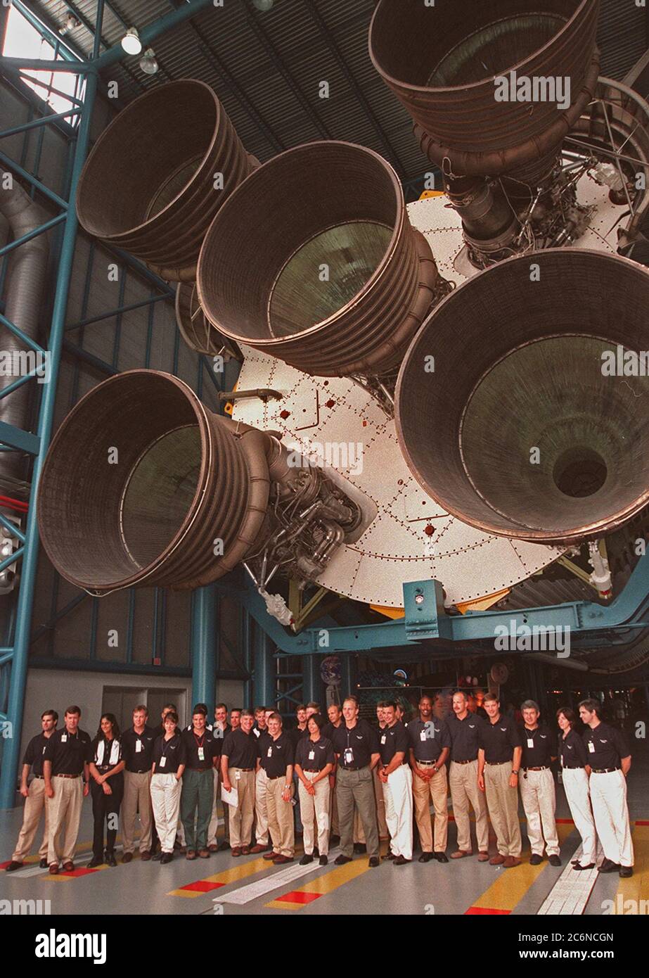 Al Centro Apollo/Saturno V, alcuni dei 1998 astronauti candidati della classe (gruppo 17) si allineano per una foto mentre si levano sotto i motori del razzo Saturno V. La classe si trova presso il KSC per attività di formazione, tra cui addestramento antincendio e un programma di sensibilizzazione sui voli, oltre a visitare l'OPF, l'impianto di lavorazione SSME, il VAB, lo SSPF, le piazzole di lancio, il SLF, il centro Apollo/Saturn V e la sede dell'equipaggio Foto Stock