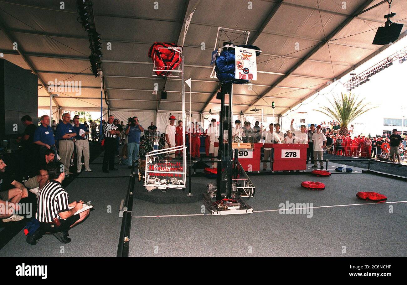 Durante le partite finali della competizione robotica regionale del sud-est del 1999 presso il KSC Visitor Complex, arbitri e giudici (magliette blu a sinistra) osservano due robot che sollevano i dischi a cuscino ad un'altezza di 8 metri, uno degli obiettivi della competizione. Direttore aggiunto del KSC per il lancio e l'elaborazione del payload Loren Shriver è uno dei giudici. Trenta scuole di tutto il paese si sono converse al KSC per l'evento che contrappone i robot gladiatori in una competizione di stile atletico. I robot devono recuperare i dischi dal pavimento, salire su una piattaforma (con bandiere), così come Foto Stock