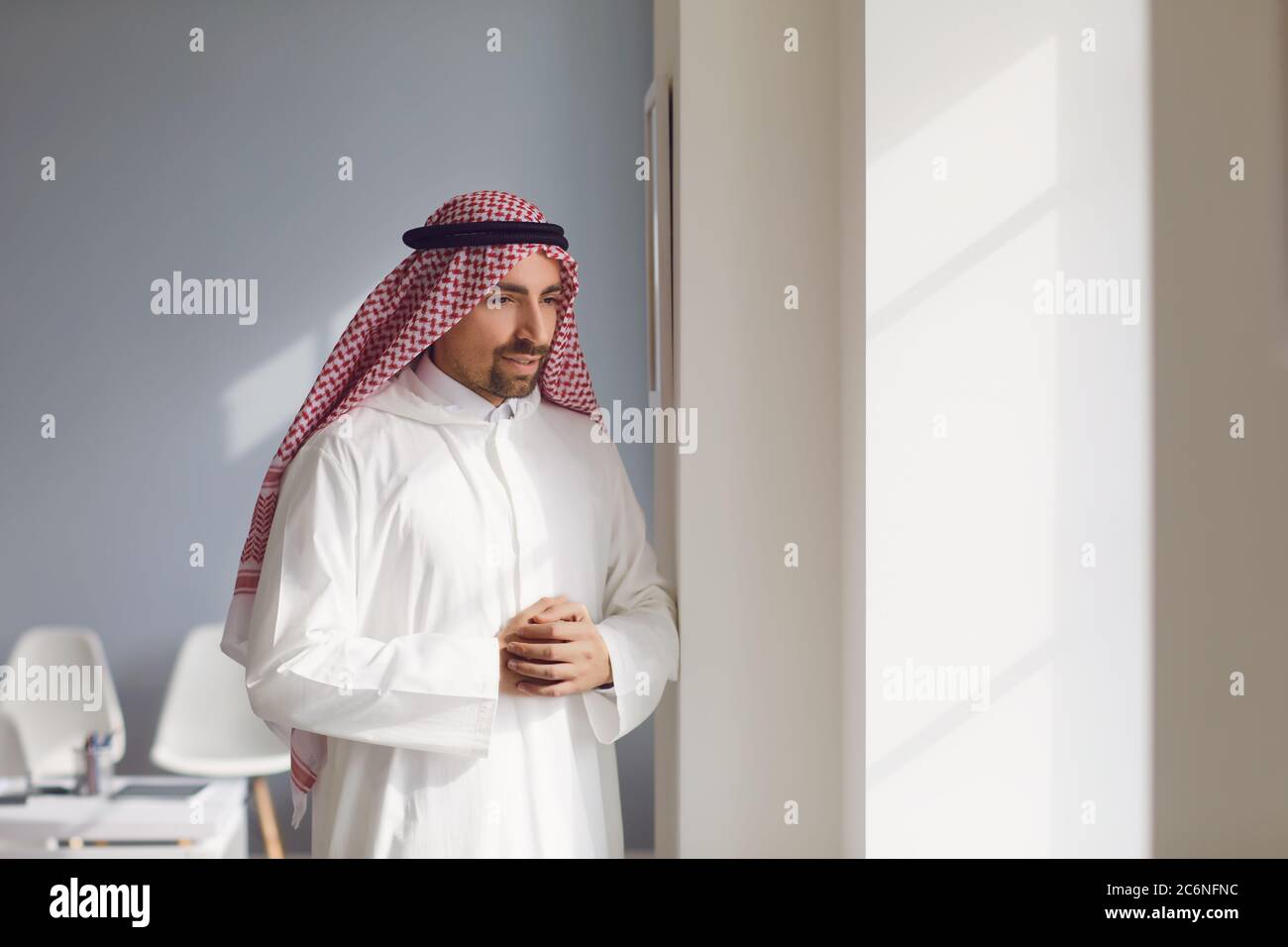 L'uomo arabo penoso guarda fuori la finestra in un ufficio bianco Foto Stock