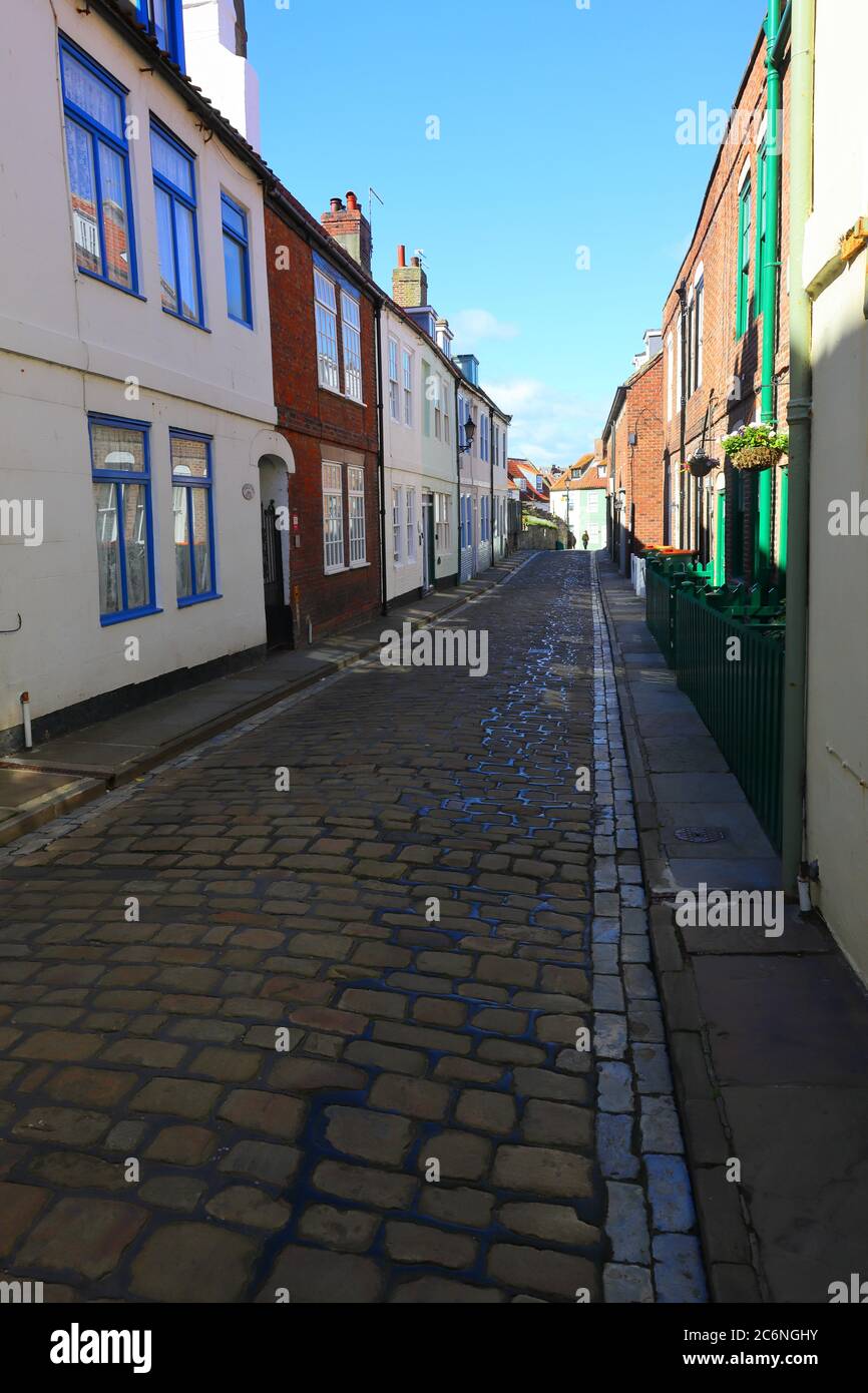 Cobbled Street con cielo blu e case a schiera a Whitby, North Yorkshire, Inghilterra, Regno Unito Foto Stock