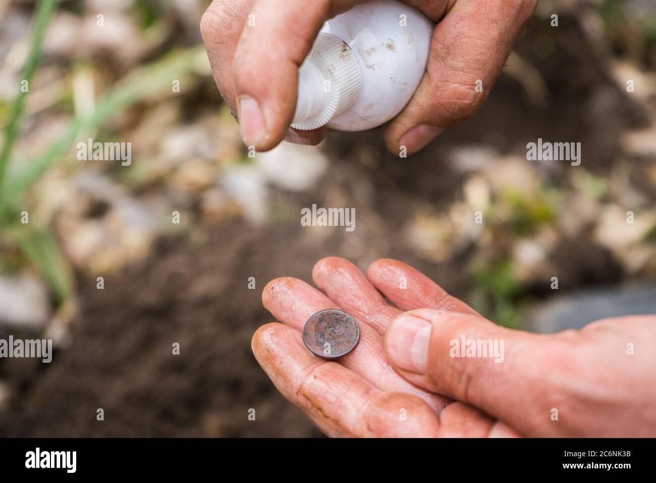 l'archeologo digger trovò una vecchia moneta antica e la lavò. Foto Stock