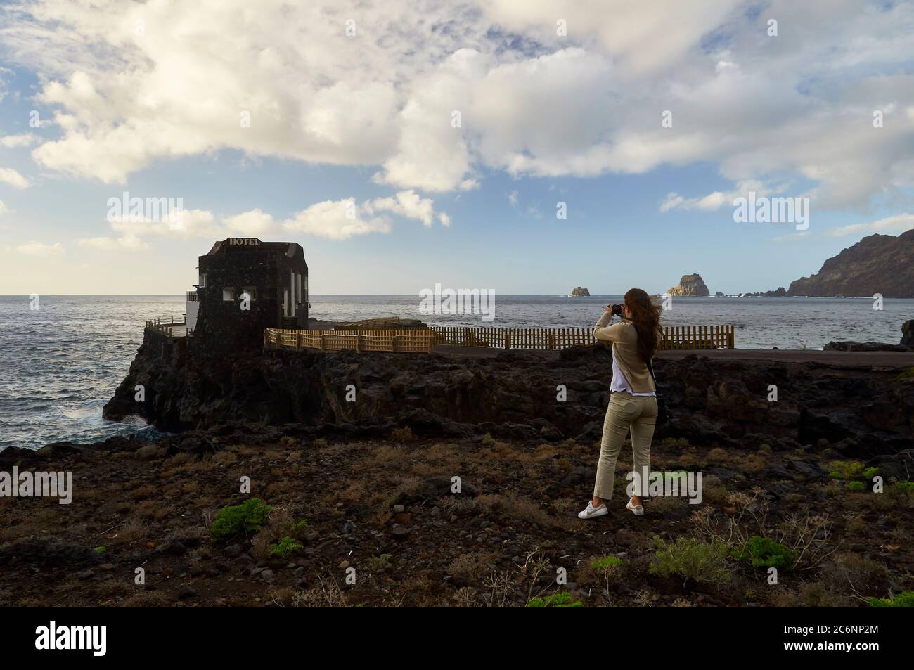 Giovane donna che fotografa l'Hotel Punta Grande, l'albergo più piccolo del mondo (Las Puntas, El Hierro, Isole Canarie, Mare Atlantico, Spagna) Foto Stock