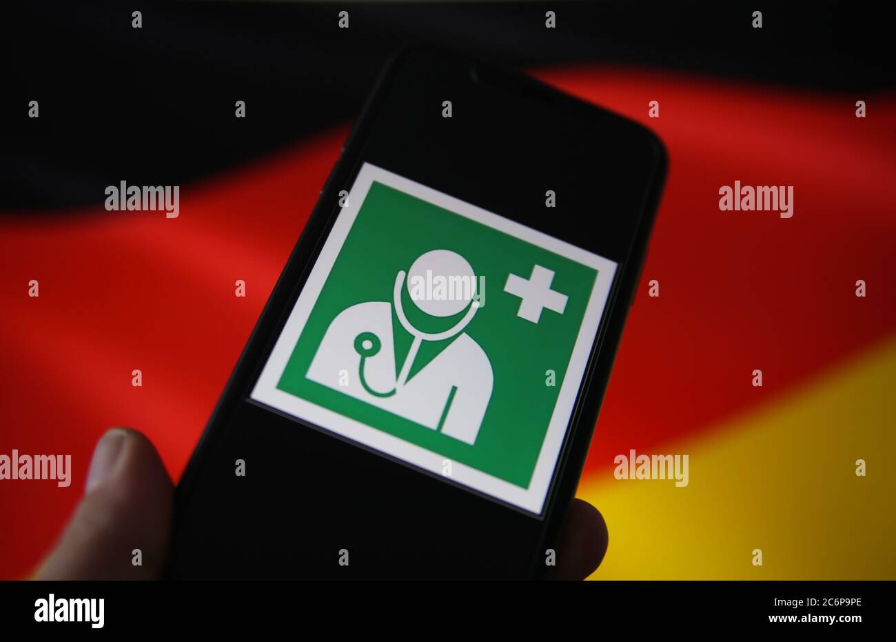 Viersen, Germania - 9 luglio. 2020: Vista sullo schermo isolato del telefono cellulare con il simbolo internazionale del medico e della salute. Bandiera tedesca sventolata Foto Stock