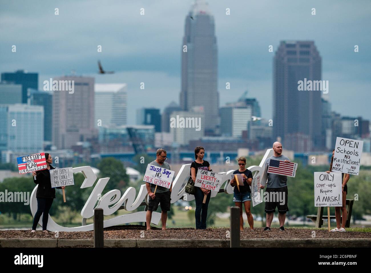 Cleveland, Ohio, Stati Uniti. 11 Luglio 2020. La gente è vista al segno scritto di Cleveland durante una 'protesta di mandato di Mask,' ospitata da TERESA MCINNIS BIANCO (all'estrema sinistra) e KEVIN FREEMAN (terzo da destra) Sabato, 11 luglio 2020 a Edgewater Park, a Cleveland, Ohio. La città di Cleveland e la contea di Cuyahoga è attualmente sotto un allarme rosso, secondo l'Ohio Public Health Advisory System, che consiglia di indossare una maschera mentre in pubblico e in altre aree congregate. Il governatore Mike DeWine ha adottato il nuovo sistema di allarme con codice colore basato su mappa che aiuta a evidenziare gli hotspot COVID più caldi in una contea a seconda della contea Foto Stock