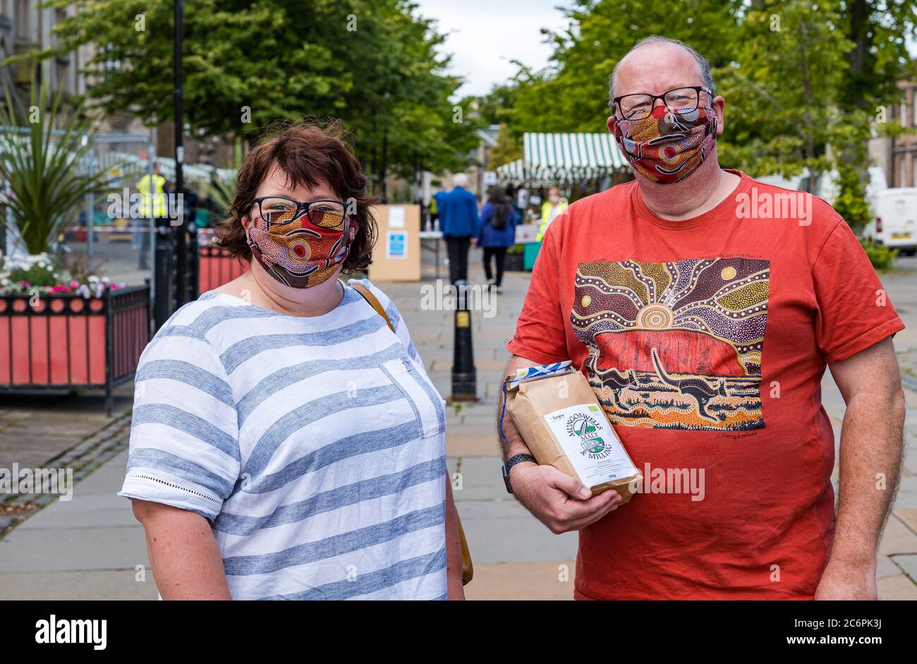 Una coppia che indossa maschere di corrispondenza fatte in casa al mercato agricolo durante la pandemia di Covid-19, Haddington, East Lothian, Scozia, Regno Unito Foto Stock