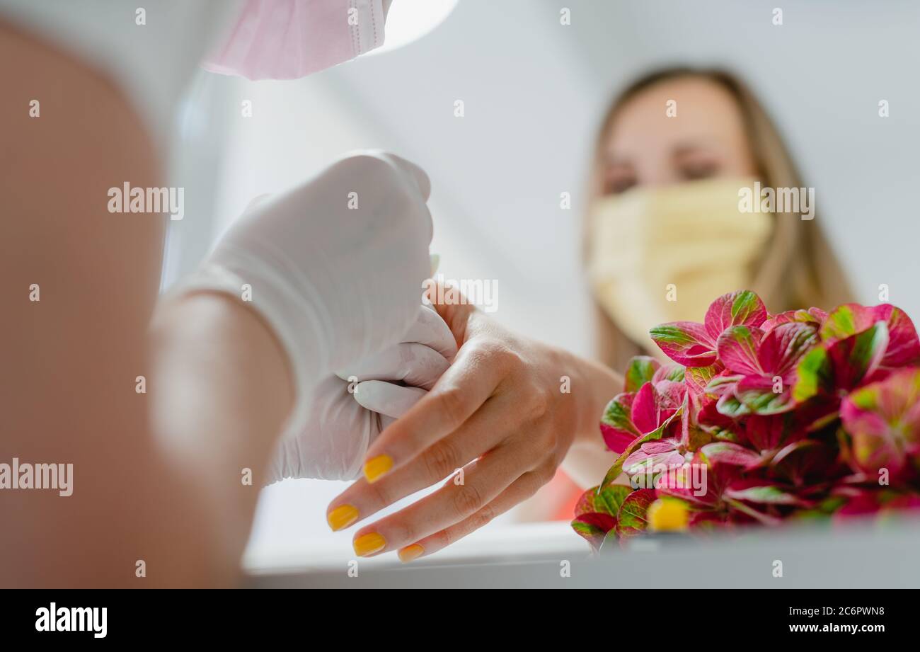 Cliente in studio di unghie con maschera protettiva Foto Stock