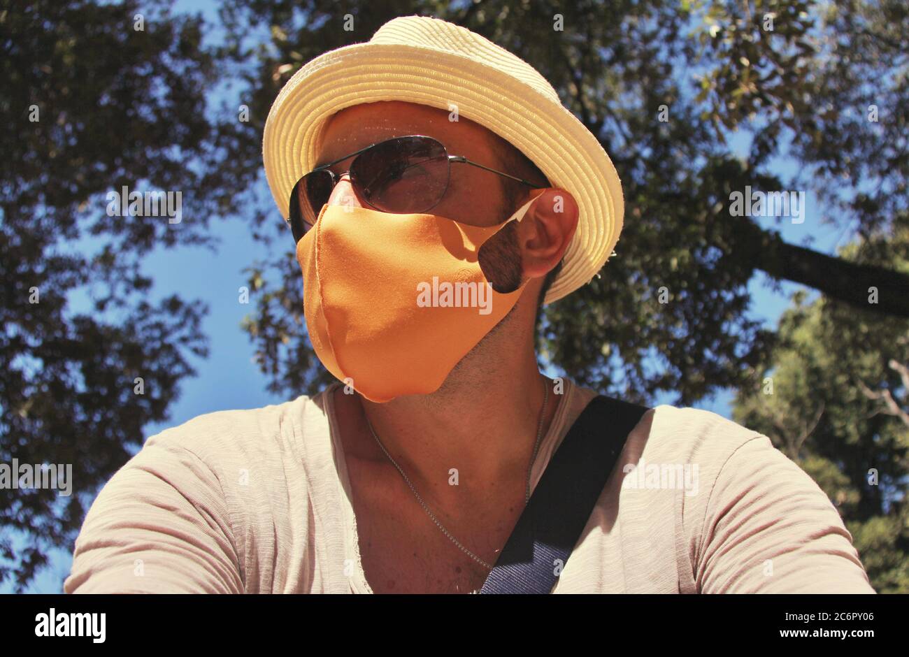 uomo italiano che indossa una maschera chirurgica gialla mentre si siede in un parco cittadino Foto Stock