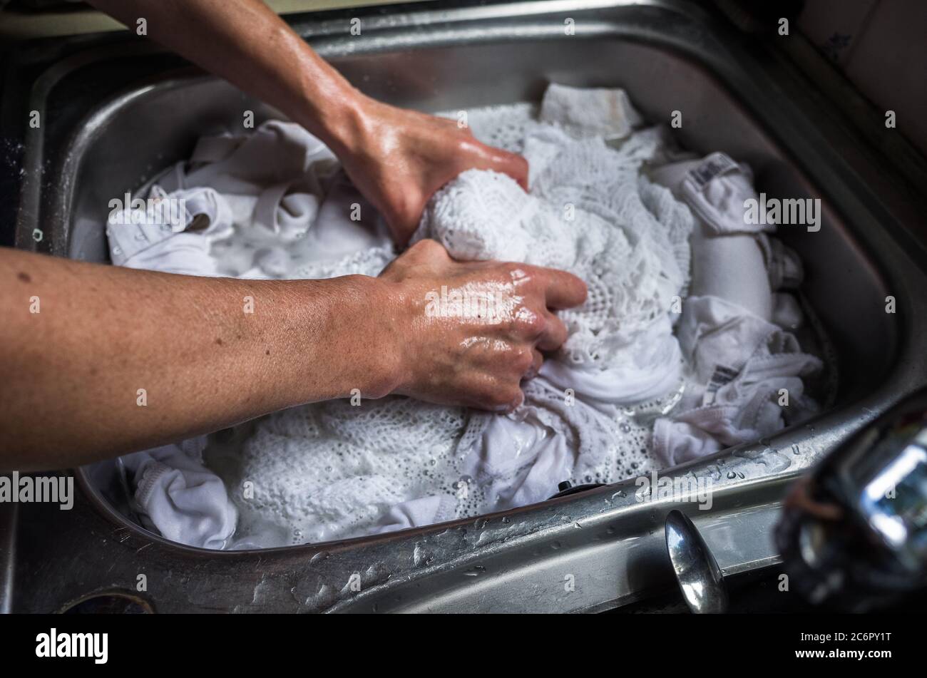 Lavare i bianchi della lavanderia a mano in un lavello cromato. Foto Stock