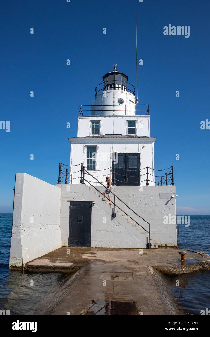 Faro di Manitowoc North Breakwater a Manitowoc, Wisconsin nel mese di luglio con la ragazza sui gradini, verticale Foto Stock