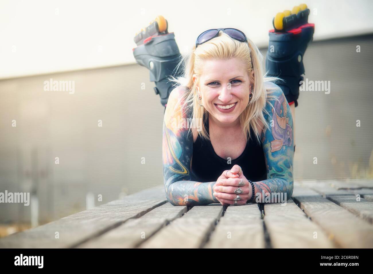 Donna bionda tatuata con lame a rullo Foto Stock