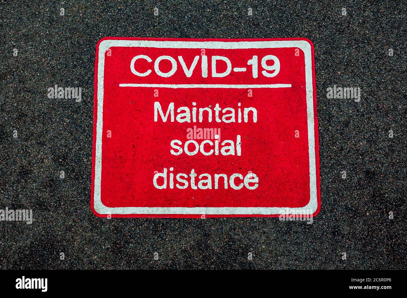 Covid-19 mantenere Social Distance Road e marciapiede segno nel Regno Unito. Coronavirus mantenere Social distanza pavimentazione segno. Foto Stock