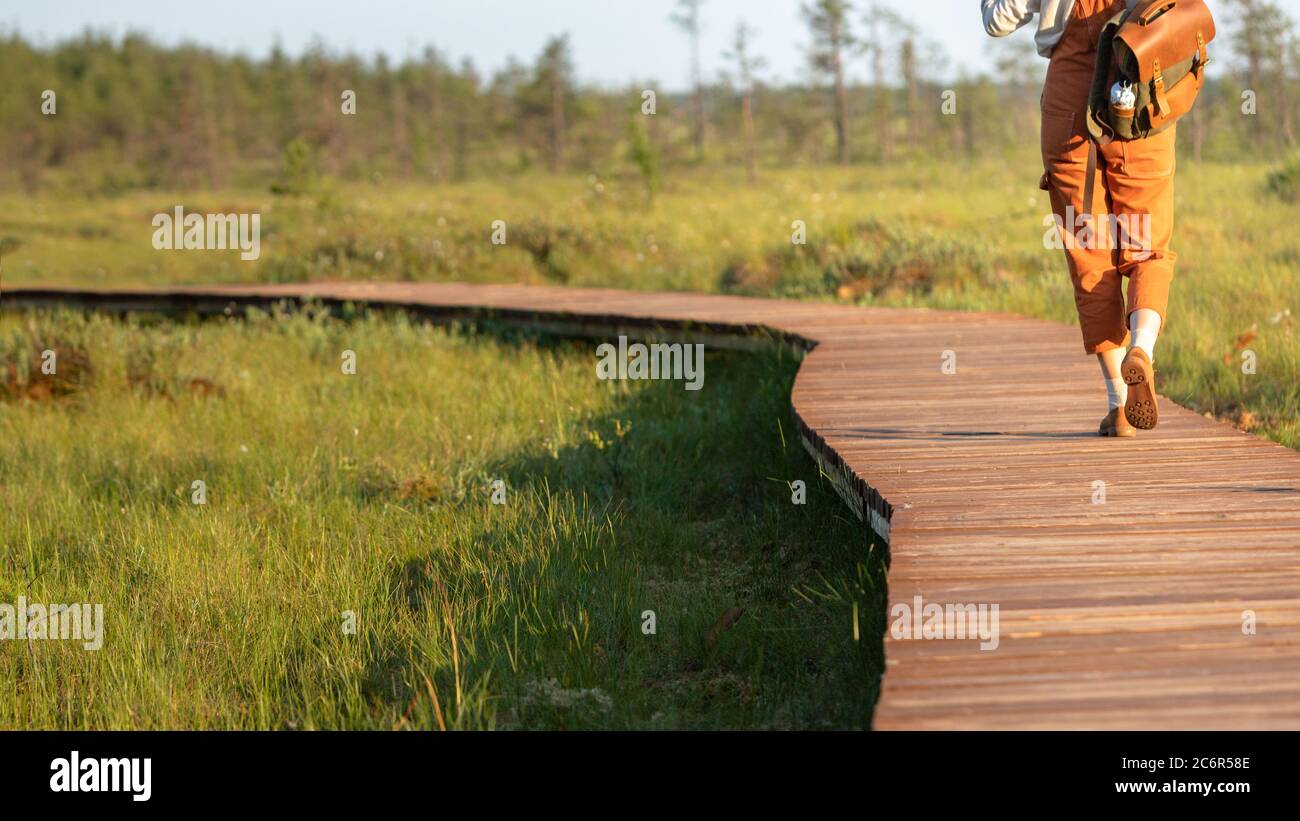 Donna con zaino su sentiero ecologico escursionistico in estate, tiro corto. Naturalista esplorando la fauna selvatica e avventura ecoturismo camminando lungo il percorso attraverso Foto Stock