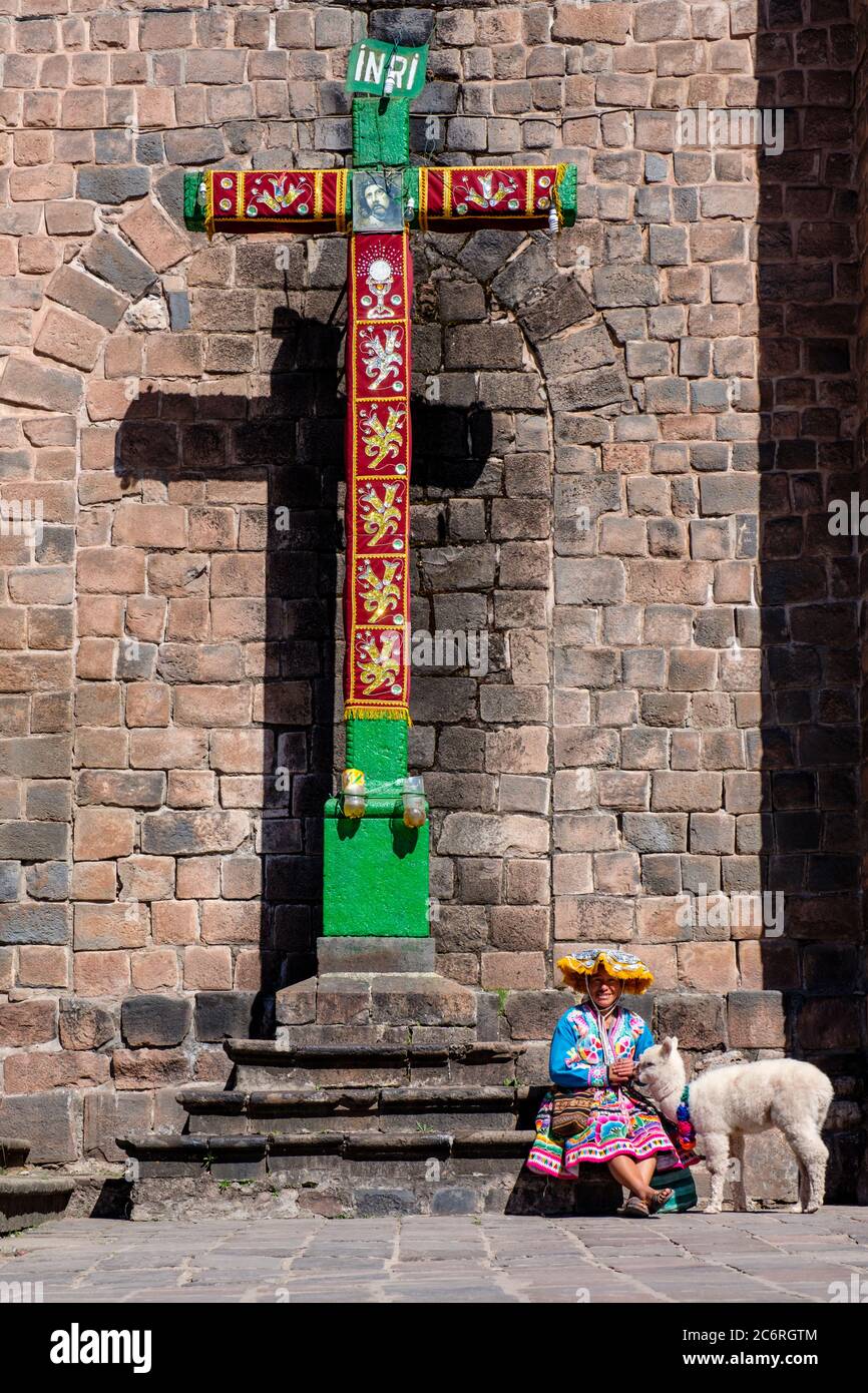 Donna indigena peruviana che indossa abiti tradizionali con un alpaca, Convento de San Francisco de Asis de Cusco, croce, crocifisso, Perù Foto Stock