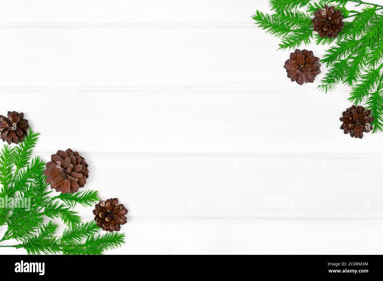 Rami di albero di Natale con coni di pino su tavola di legno bianco. Spazio di copia. Sfondo cornice Natale Foto Stock