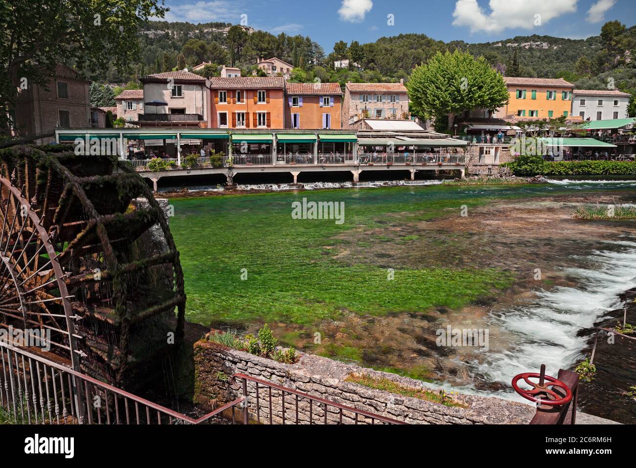 Fontaine-de-Vaucluse, Provenza-Alpi-Costa Azzurra, Francia: Paesaggio del villaggio con il fiume Sorgue verde e una ruota mulino ad acqua Foto Stock