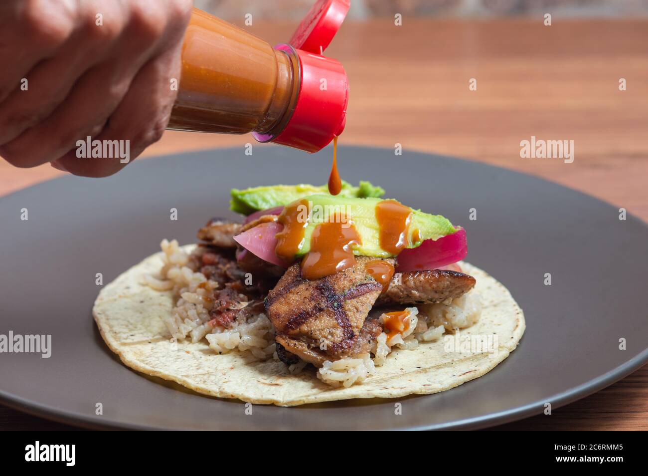 POC Chuc, cucina messicana. Piatto di maiale dello Yucatecan marinato nel succo di agrumi, mettendo salsa piccante su un taco Foto Stock