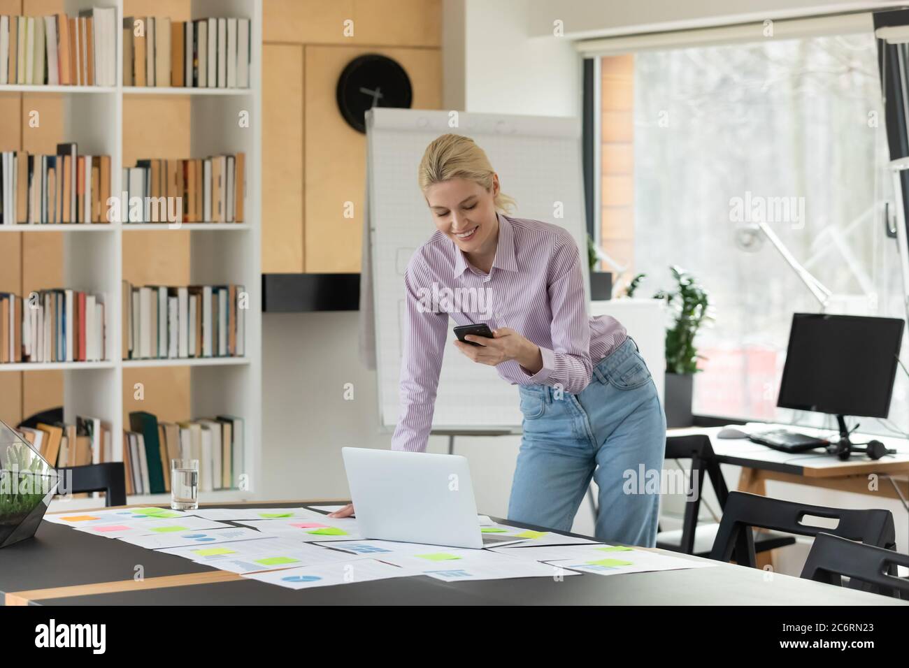 Sorridente donna caucasica lavoro su gadget in ufficio Foto Stock