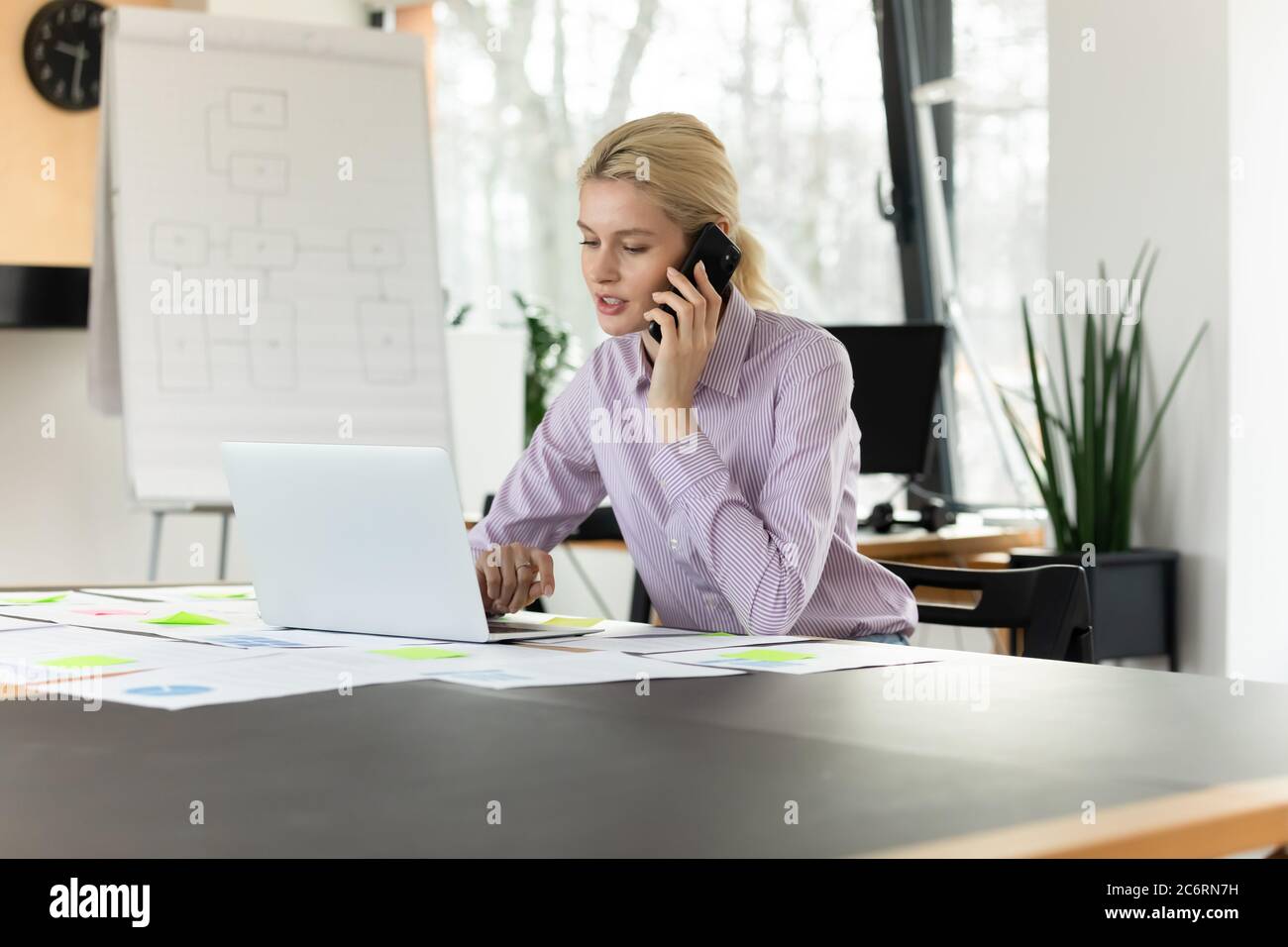 Uomo d'affari caucasico lavoro su computer parlare su cella Foto Stock