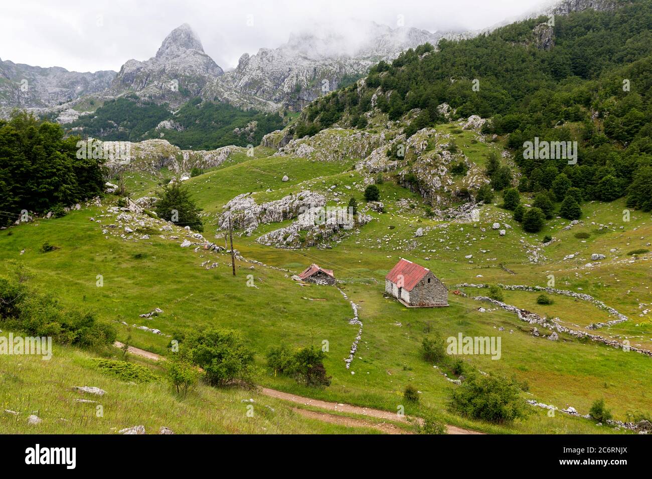 Vista sul prato con pascoli e capanne tradizionali e splendida vista sulle montagne del lago Bukumirsko, Montenegro Foto Stock
