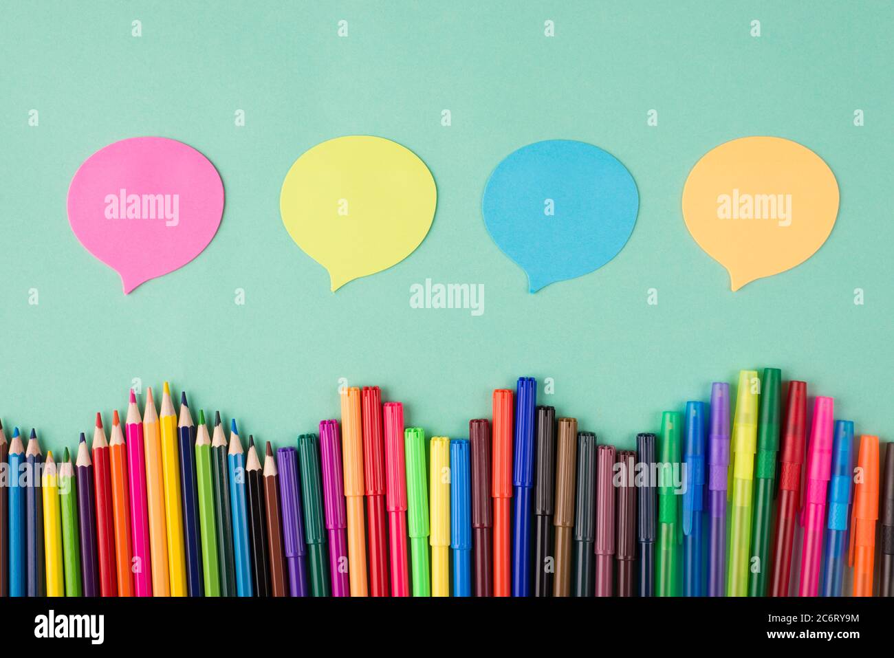 Condividere idee e pensieri. In alto vista dall'alto foto di colorati matite pennarelli e bolle di pensiero isolate sullo sfondo turchese Foto Stock