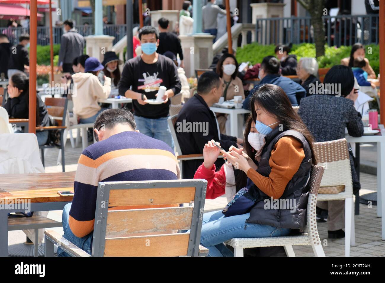 Folla di persone che si siede al ristorante all'aperto, indossando una maschera protettiva per prevenire il coronavirus Foto Stock