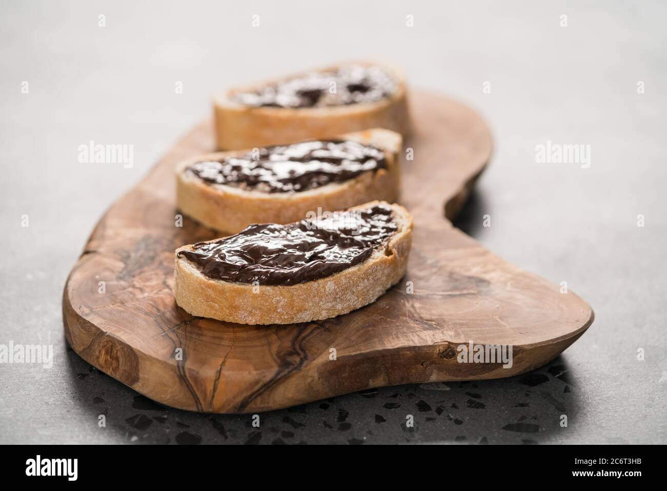 Ciabatta rustica con crema di cioccolato biologica su tavola di ulivo Foto Stock