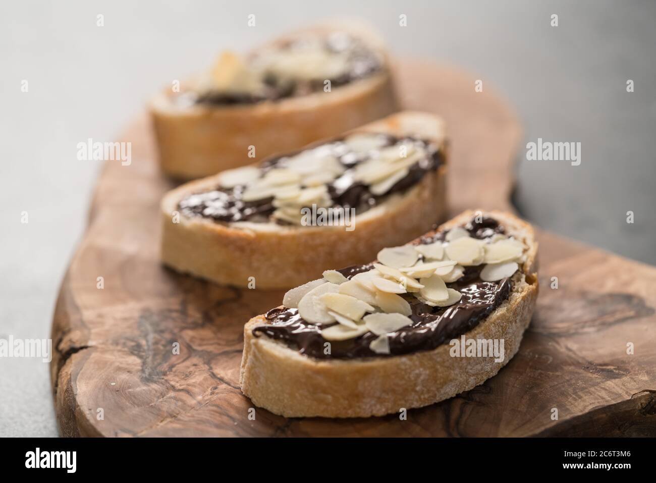 Ciabatta rustica con crema di cioccolato organico e scaglie di mandorle su tavola di ulivo, fuoco basso Foto Stock