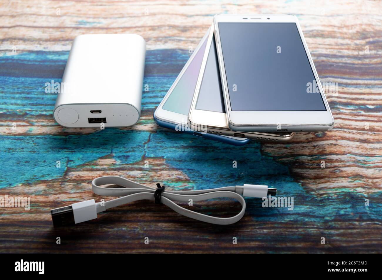 Powerbank con spina e diversi smartphone. Power bank universale per tutti gli smartphone. Vista angolata. Foto Stock