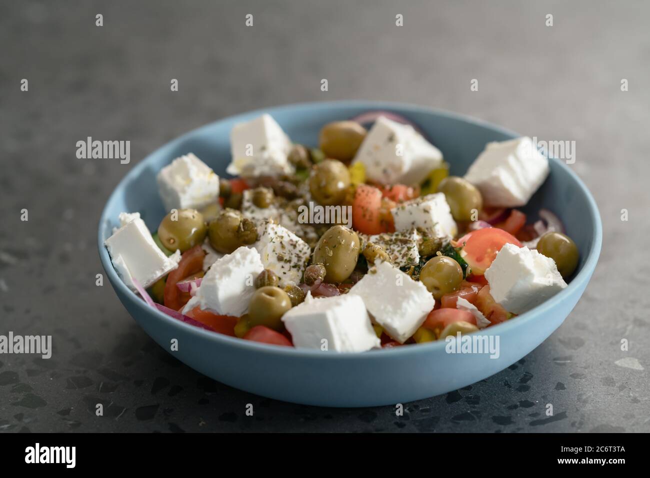 Insalata greca classica in ciotola blu su fondo di cemento Foto Stock