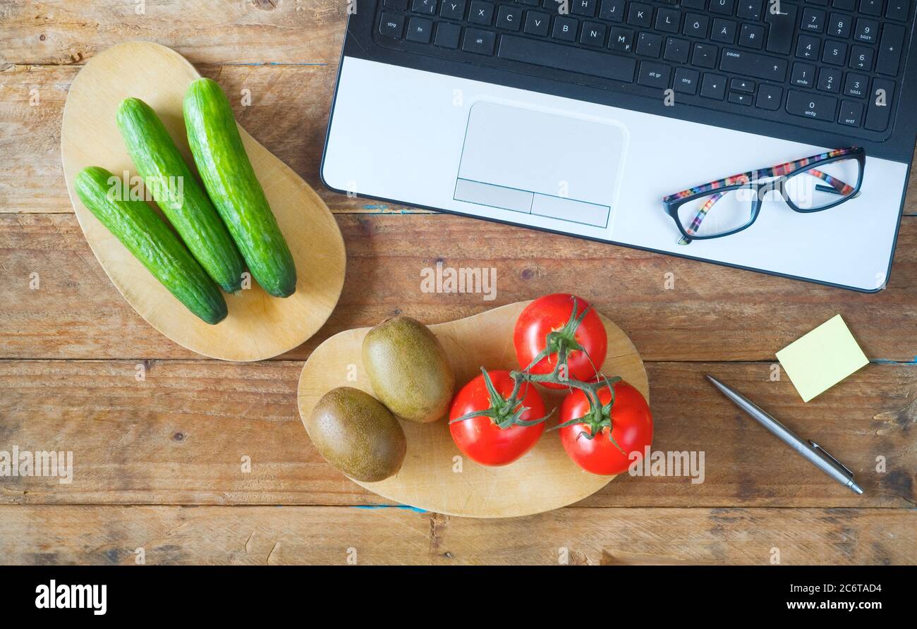 Cibo sano sul tavolo da lavoro con laptop, verdure e frutta, pausa pranzo sana Foto Stock