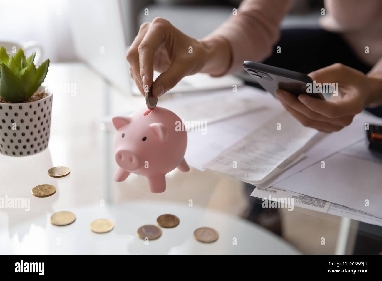 Primo piano di donna ha messo moneta in una banca di piccini Foto Stock
