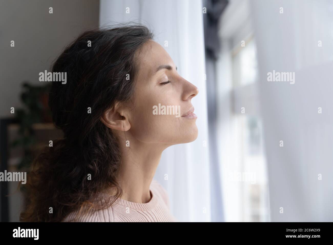 Giovane donna pacifica medita con gli occhi chiusi a casa Foto Stock