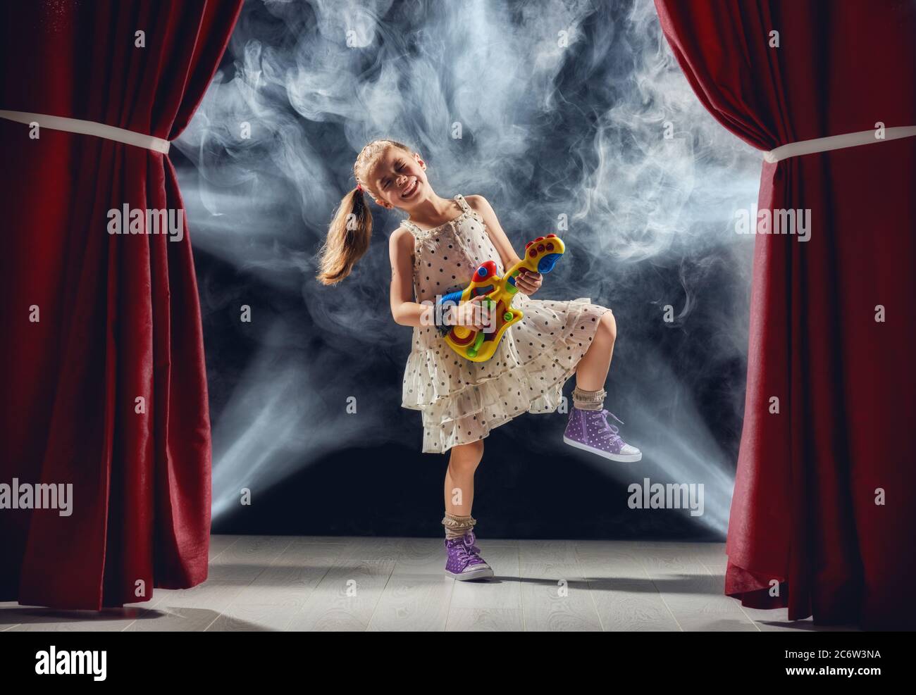 Carina bambina ragazza che suona la chitarra sul palco. Capretto sogna di diventare un musicista rock. Foto Stock