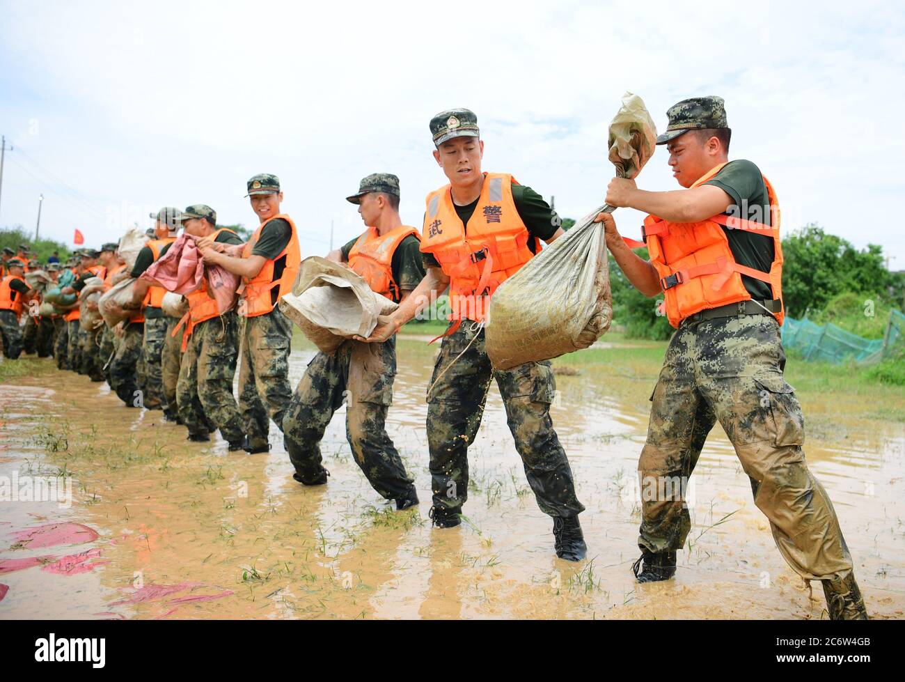 Poyang, Cina. 12 luglio 2020. I poliziotti armati spostano sacchi di sabbia per il rinforzo della diga nella contea di Poyang, nella provincia di Jiangxi della Cina orientale, 12 luglio 2020. Il lago Poyang, il più grande lago d'acqua dolce della Cina, situato nella provincia orientale di Jiangxi, ha visto il suo livello d'acqua salire a un record la domenica, secondo il dipartimento provinciale delle risorse idriche. Domenica, intorno alle 12:00, il livello dell'acqua nella stazione idrologica di Xingzi del lago salì a 22.53 metri, 0.01 metri più in alto del record del 1998, e continuò a salire, ha detto il dipartimento. (Foto di Cao Xianxun/Xinhua) Credit: Xinhua/A. Foto Stock