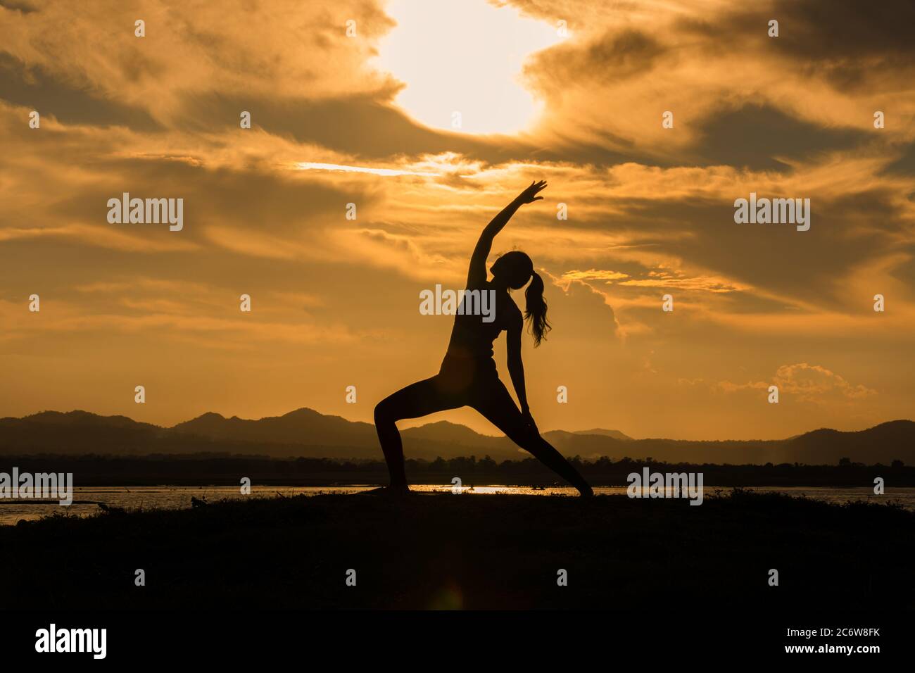 Silhouette le donne asiatiche si stanno allenando con yoga fuori vicino al fiume in serata. Foto Stock