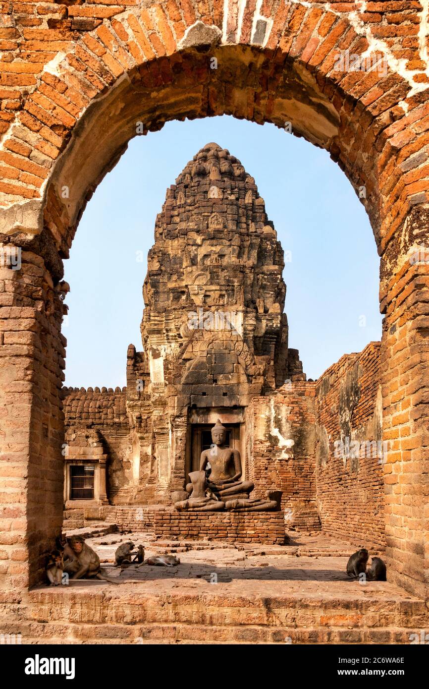 Macaco (Macaca fascicularis) di fronte a Jayabuddhamahanatha (Buddha Victorius, il Grande protettore) a Prang Sam Yod, Lopburi, Thailandia Foto Stock