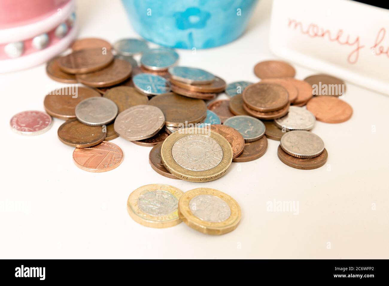 Primo piano di selezione di monete, sterline, sterline, due libbre e recinzioni con scatole di denaro Foto Stock