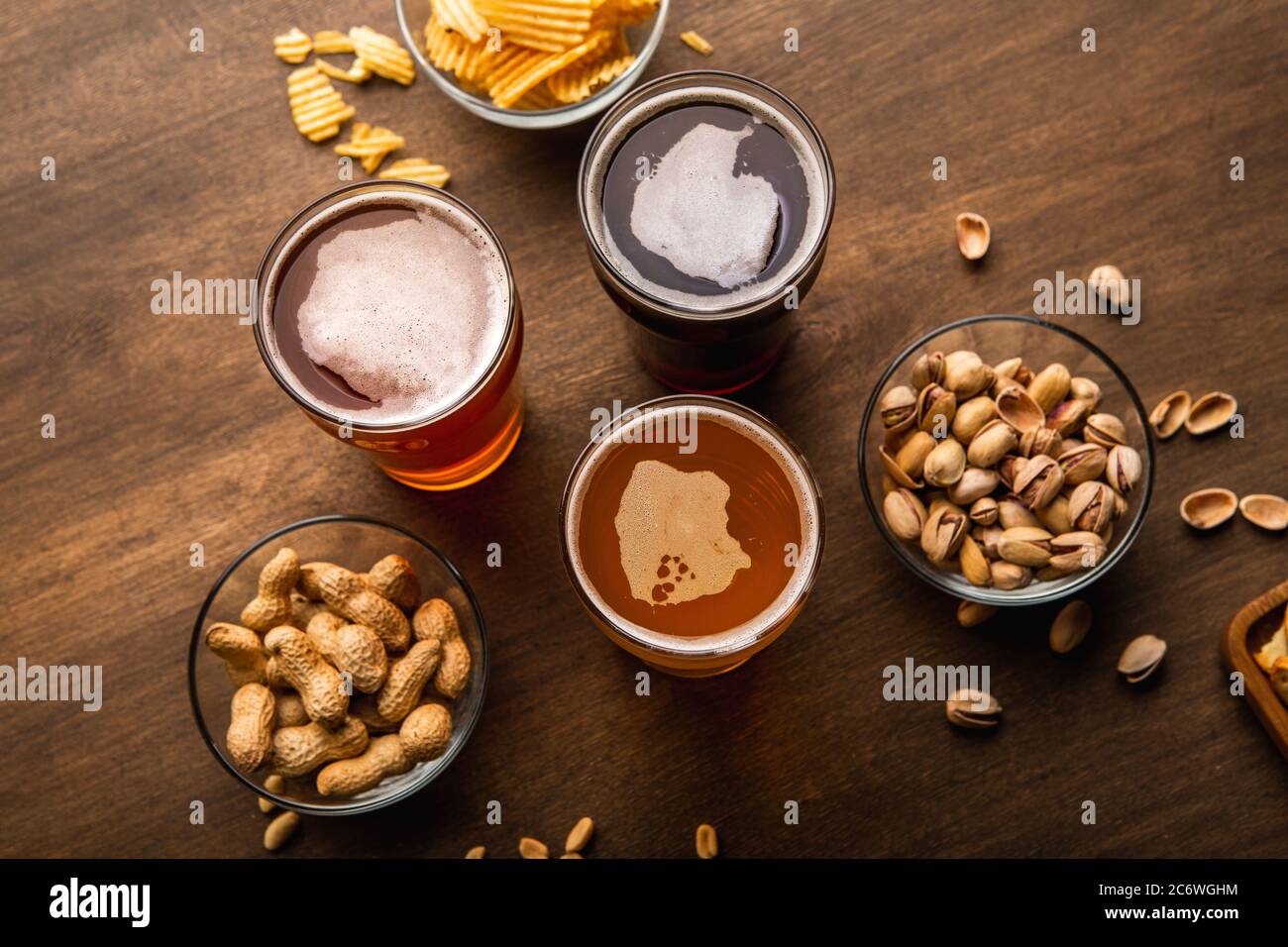 Birra scura, chiara, non filtrata in vetro su tavolo di legno con spuntini in piatti Foto Stock