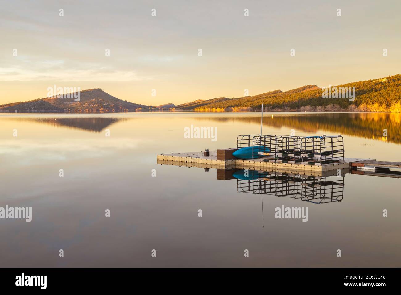 Il sole colpisce la collina sul lago di montagna all'alba. Il molo per le imbarcazioni si riflette nel lago carter situato a Loveland, Colorado Foto Stock