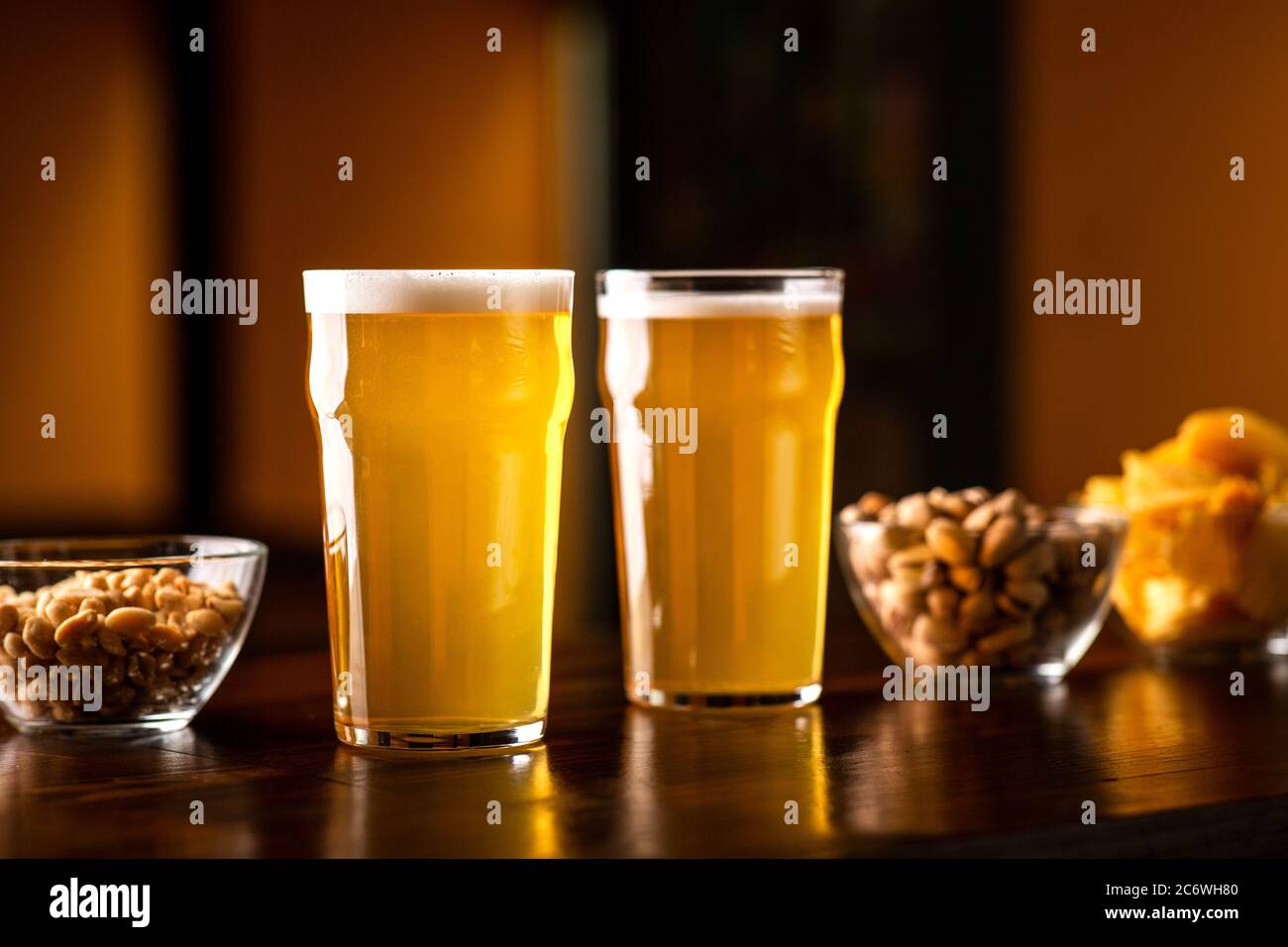 Birra business in pub. Bicchieri di lager, pistacchi, patatine e noci su tavolo in legno all'interno Foto Stock