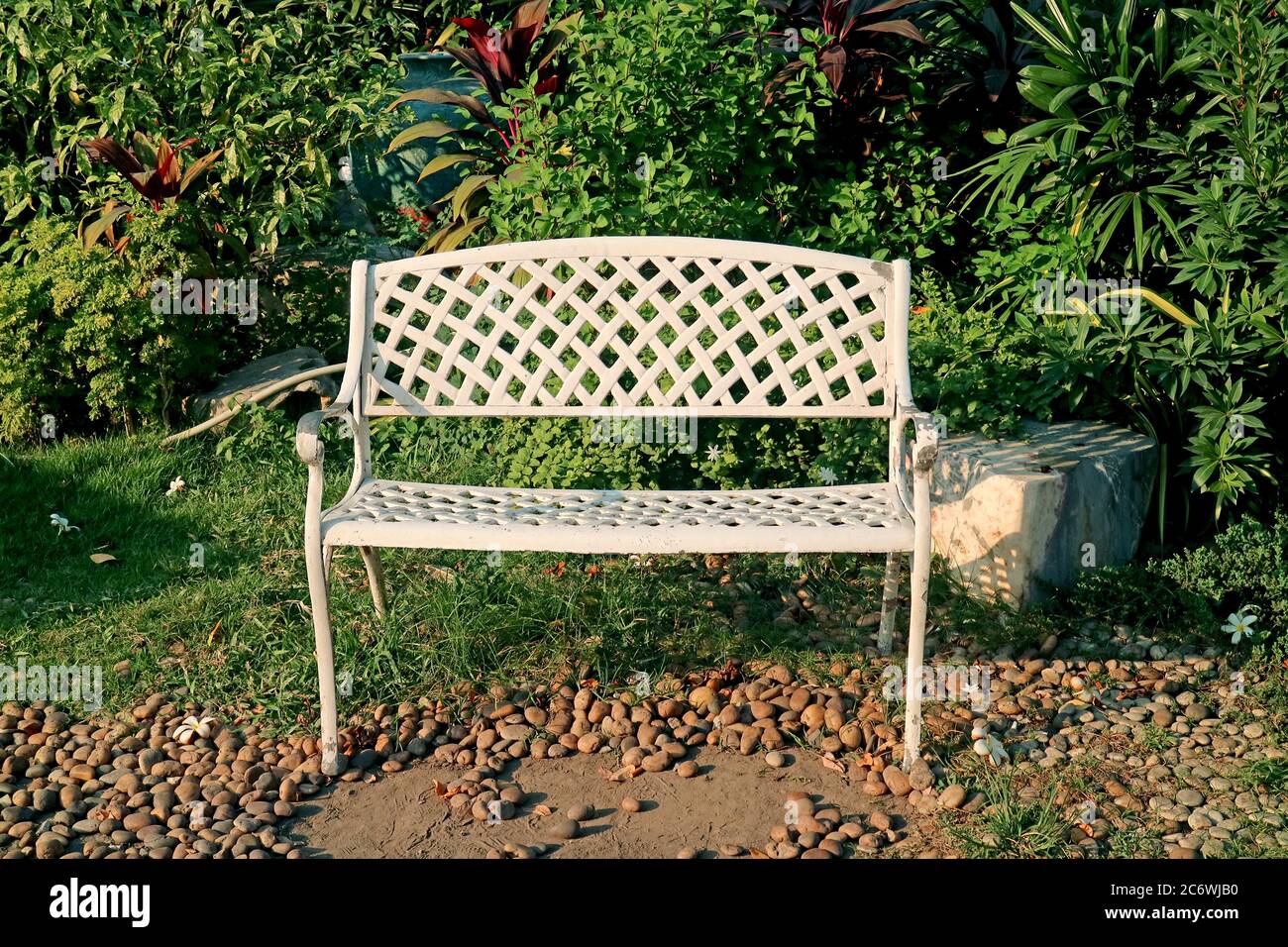 Panca vuota in ferro battuto bianco nel giardino solare Foto Stock