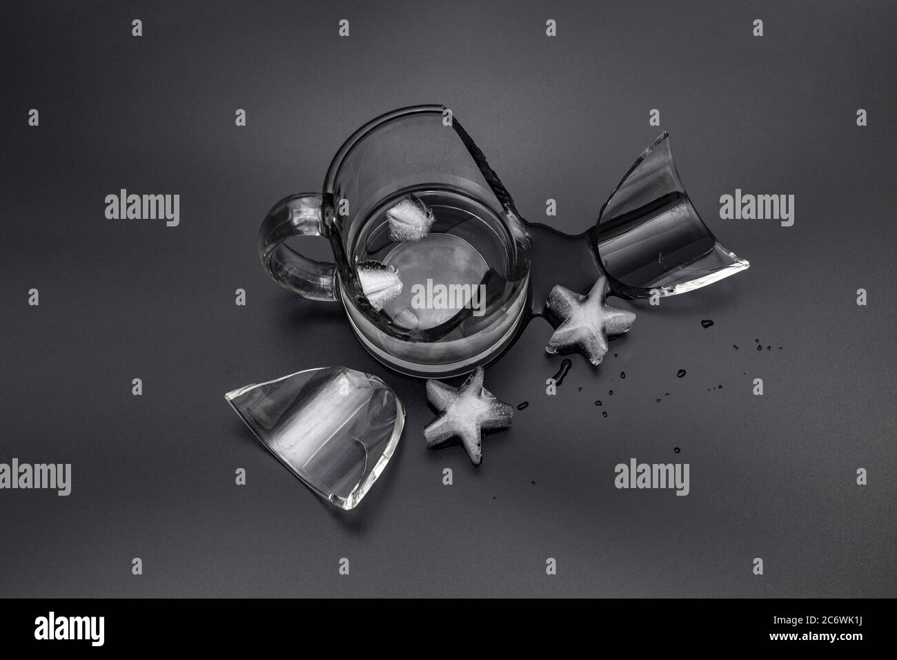 Coppa di vetro rotta con acqua e ghiaccio su fondo nero Foto Stock